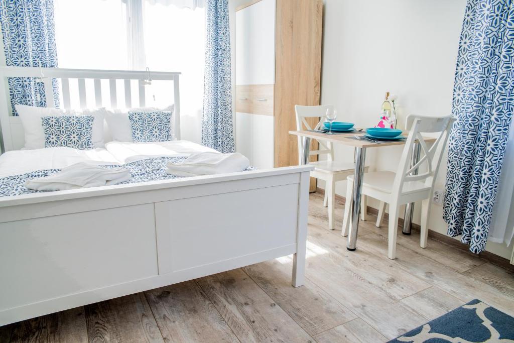 a bedroom with a white bed and a table at Apartamenty Mewa in Międzyzdroje