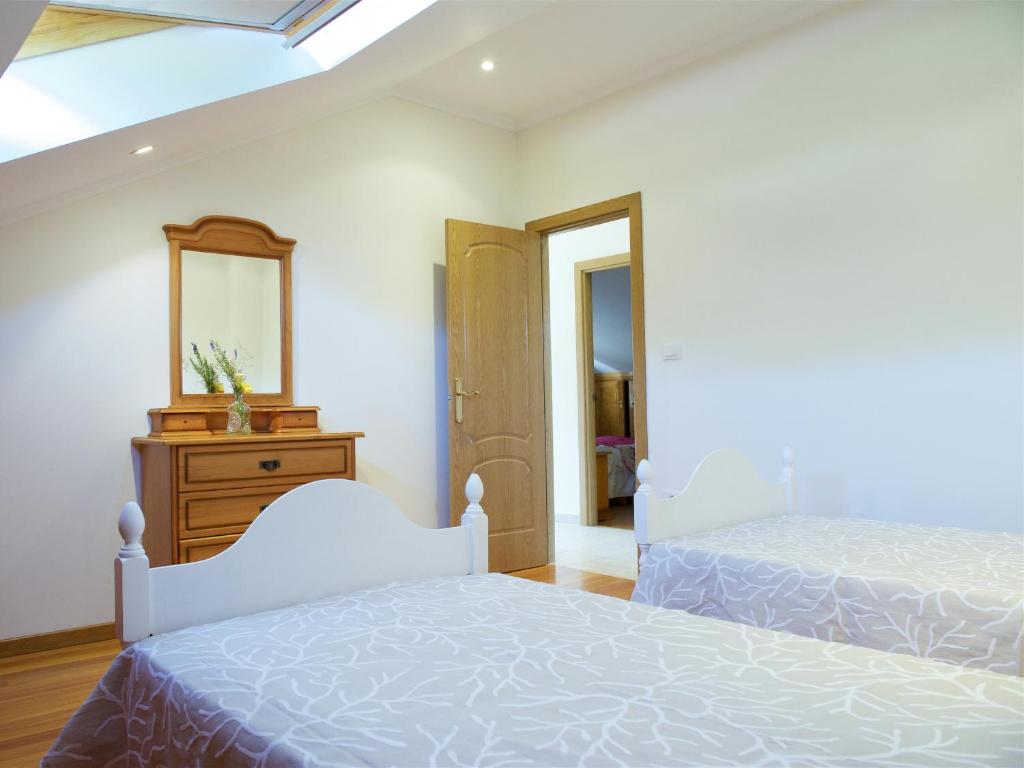a bedroom with two beds and a mirror at Vivienda de uso turístico Eido de Roque in Mondariz