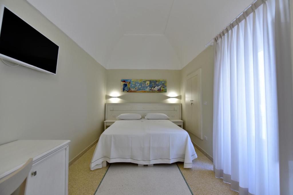 a bedroom with a white bed and a flat screen tv at Fortino San Giorgio in Gallipoli
