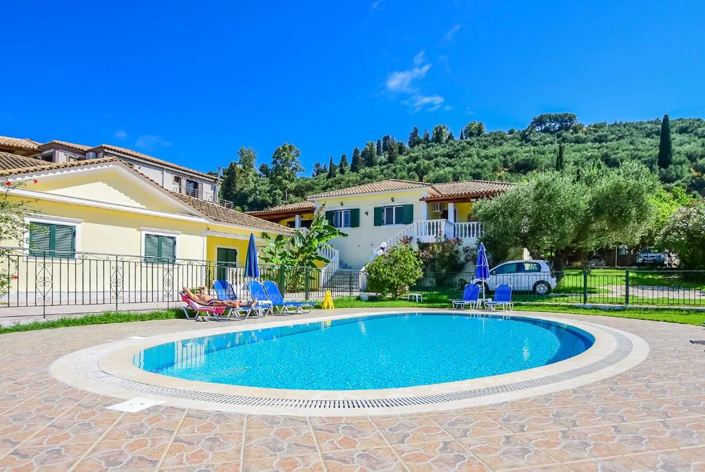 a swimming pool with chairs and a house at Tonia Apartments in Zakynthos Town