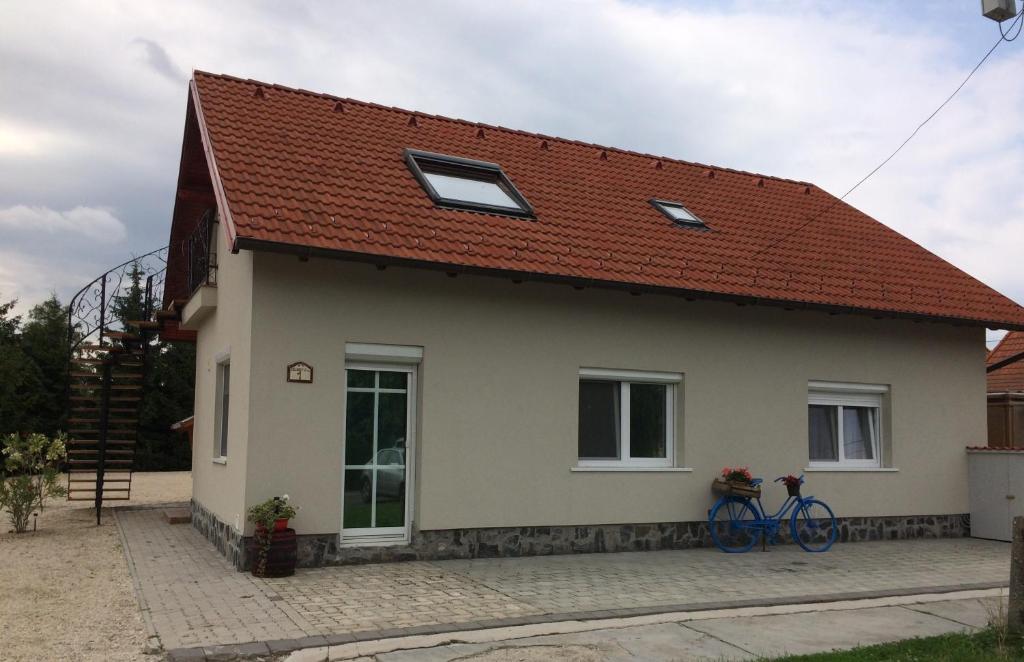 a white house with a red roof and a bicycle at Báró Berg Apartman in Kapuvár
