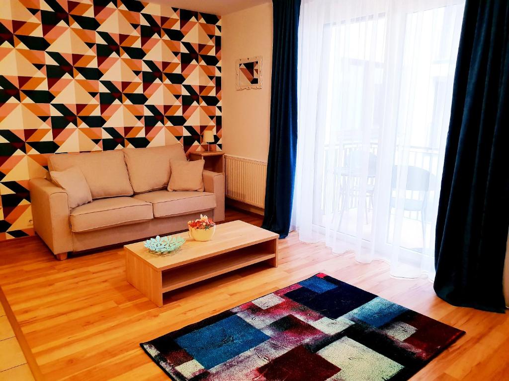 ein Wohnzimmer mit einem Sofa und einer geometrischen Wand in der Unterkunft Vagabond Apartman in Miskolc