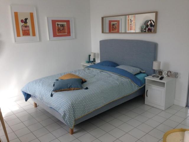 オンフルールにあるLe petit studio honfleuraisの白いフロアのベッドルーム1室(青いベッド1台付)