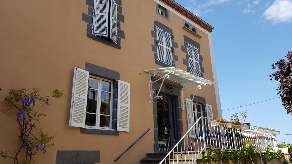 a yellow building with white shutters and a balcony at Au Coq Bleu in Mareugheol