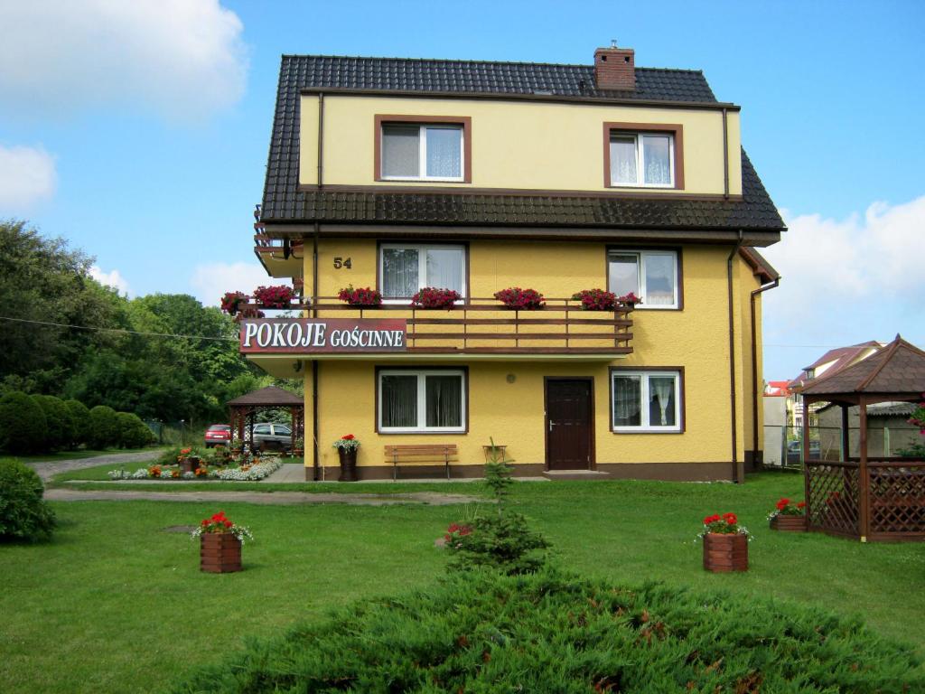 a yellow house with a sign on the side of it at Kwatery Prywatne Regina Pociask in Dziwnówek