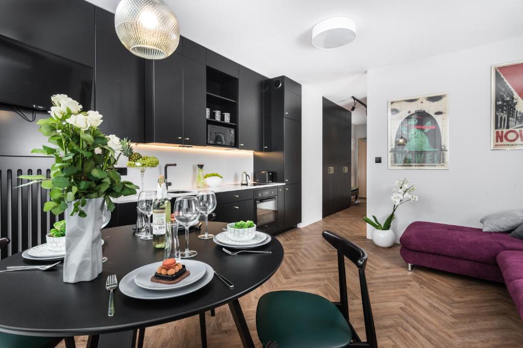 comedor y sala de estar con mesa negra y sillas en Moss Apartment, en Cracovia