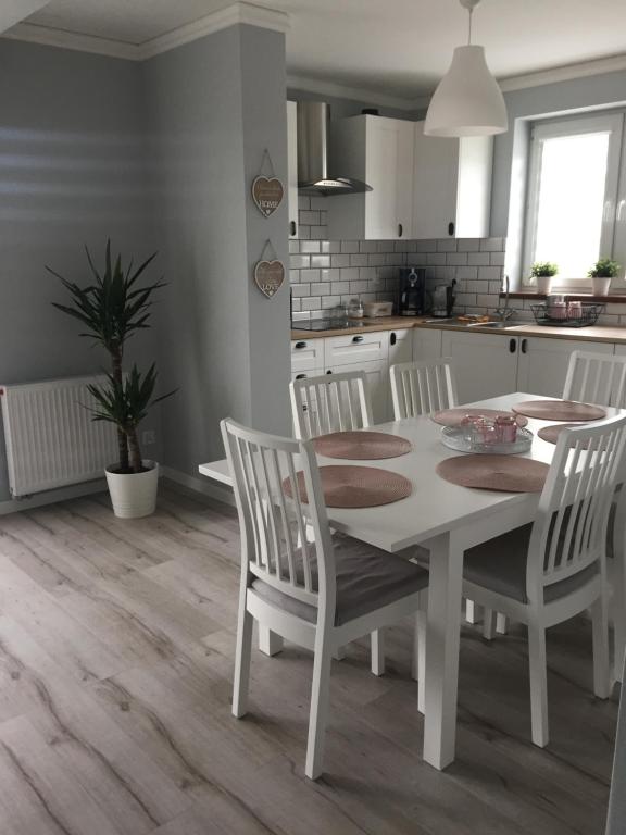 a white kitchen with a white table and chairs at Apartament Julek klimatyzowany in Oświęcim
