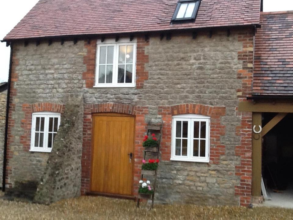 a brick house with a wooden door and two windows at 5 High Street in Temple Combe