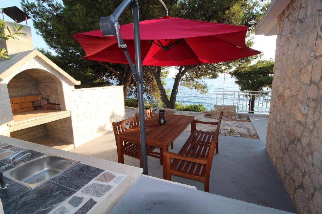 una sombrilla roja sobre una mesa y sillas en un patio en Kuća za odmor Modra oaza en Primošten