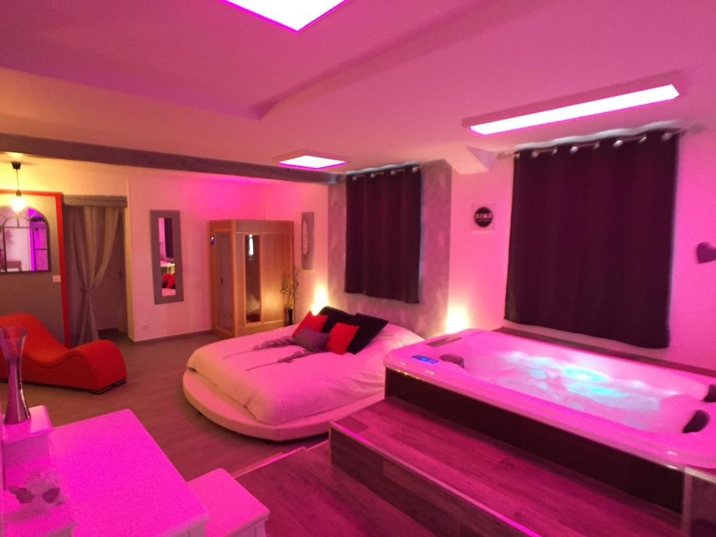 um quarto com 2 camas e iluminação rosa em Suite Cupidon- Domaine des trois châteaux em Moisenay