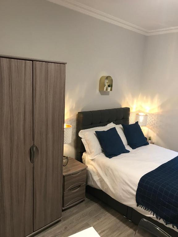 a bedroom with a bed and a wooden cabinet at Berkshire Apartments 1 Helena House Brownlow Road in Reading