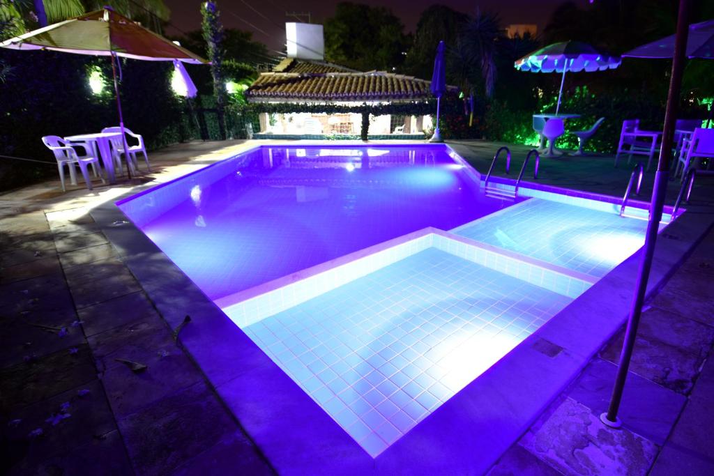 a swimming pool with purple lighting in a backyard at night at Hotel Pousada Ipitanga IV in Lauro de Freitas