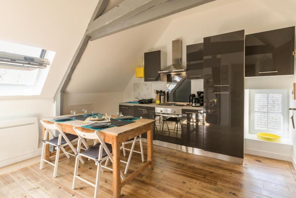 a kitchen with a wooden table and a wooden floor at Le 45 in Isigny-sur-Mer