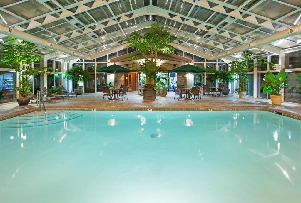 una gran piscina en un edificio con mesas y sillas en Best Western Okemos&#47;East Lansing Hotel &amp; Suites, en Okemos