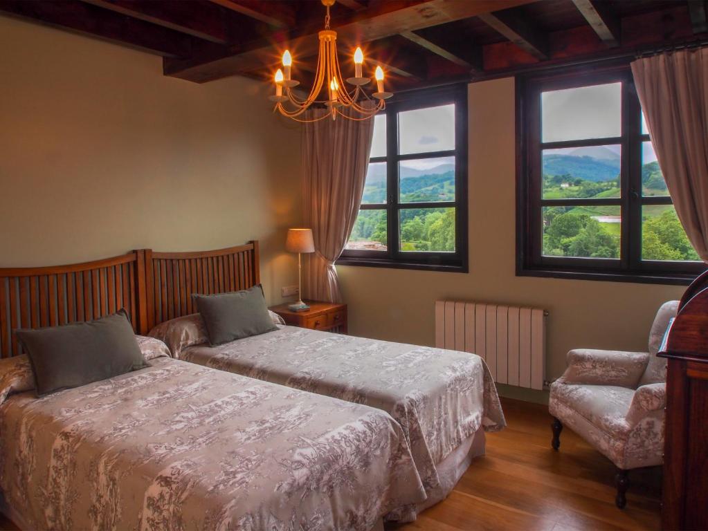 a bedroom with a bed and a chair and windows at Casas Rurales Asturias Campon Antrialgo in Infiesto