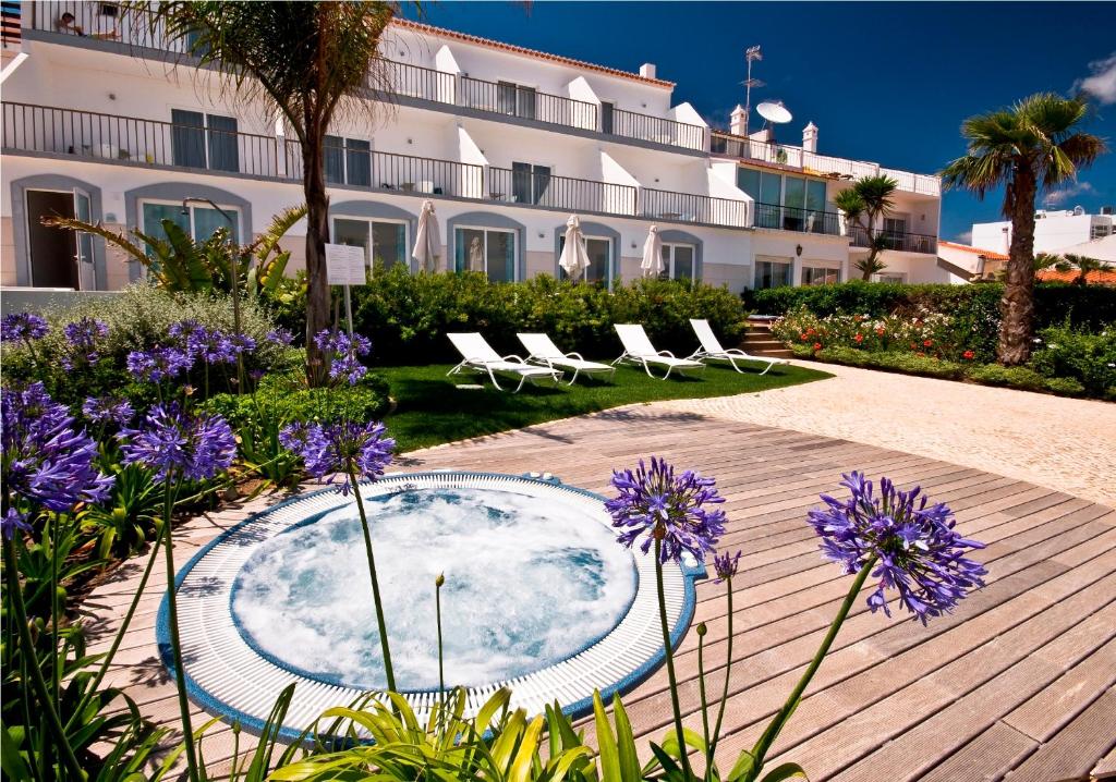 un patio con bañera de hidromasaje, sillas y flores púrpuras en Mareta View - Boutique Bed & Breakfast, en Sagres