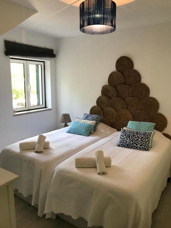 two twin beds in a room with a large headboard at Casa do Farol da Arrábida in Portinho da Arrábida