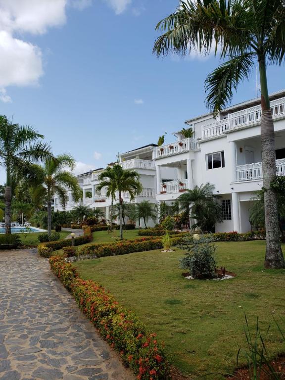a large white building with palm trees in front of it at Las Terrenas, La Fenice, Playa Popy in Las Terrenas