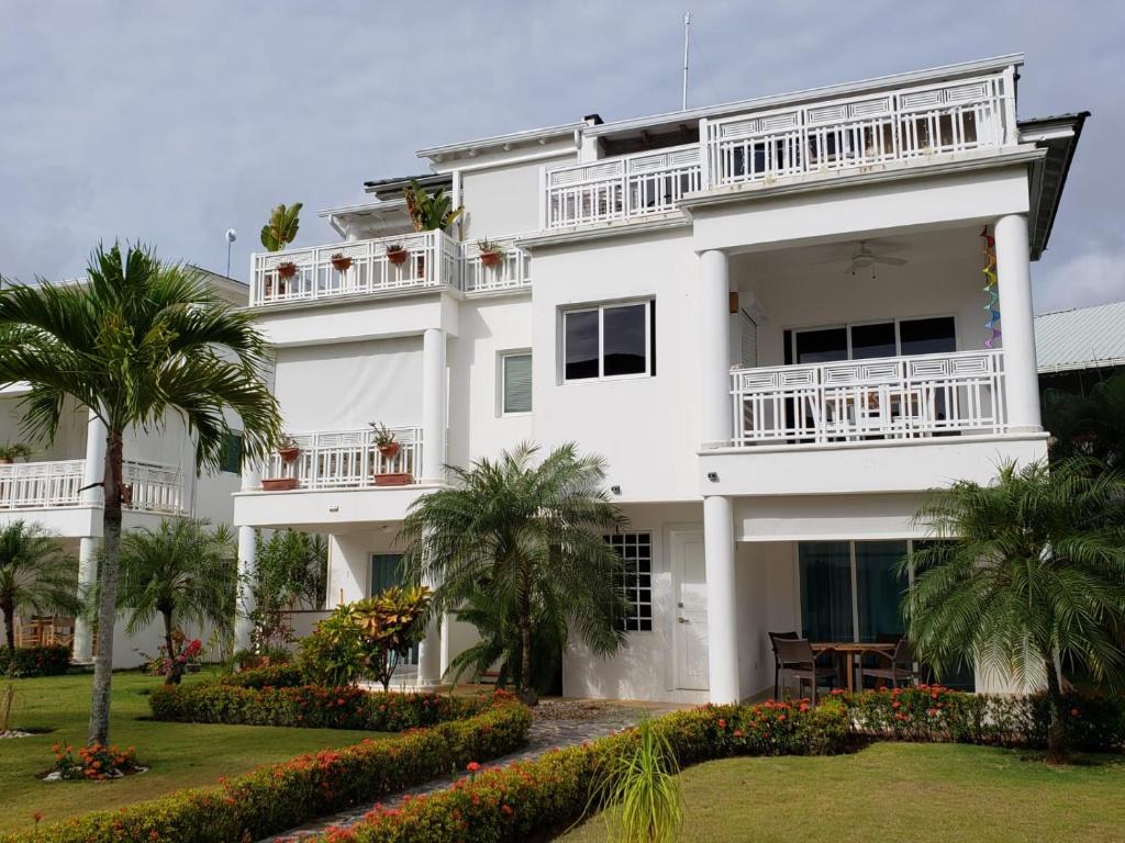 a white building with palm trees in front of it at La Fenice, Playa Popy in Las Terrenas