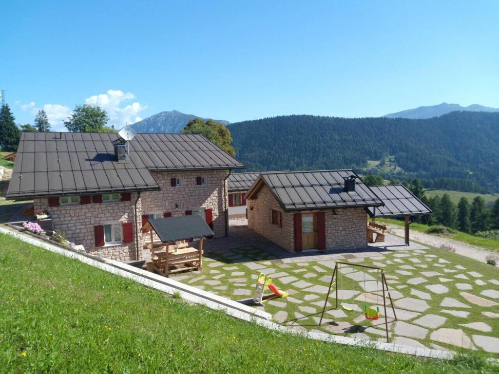 ein Haus mit Spielplatz in der Mitte eines Gartens in der Unterkunft Regensburgerhof in Castello Tesino