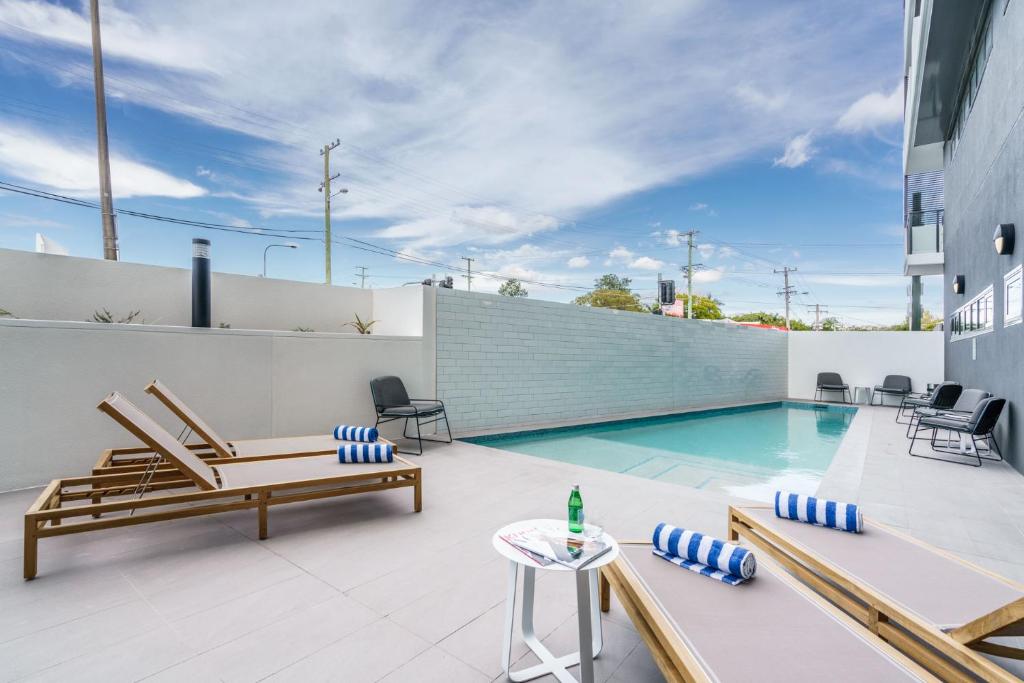 a pool with chairs, tables, and benches in it at Quest Cannon Hill in Brisbane
