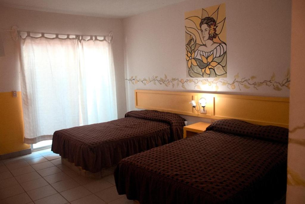 a hotel room with two beds and a painting on the wall at Hotel y R.V. Park El Moro in Loreto