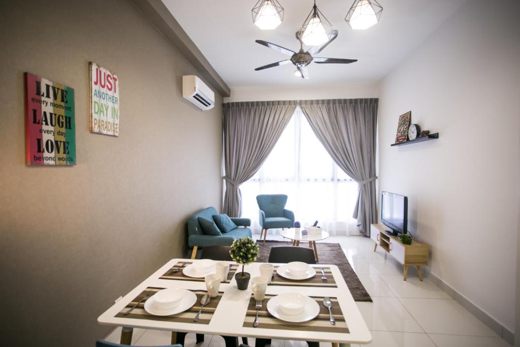 a living room with a table and chairs and a television at Econest Apartment By The one - Educity Nusajaya in Nusajaya