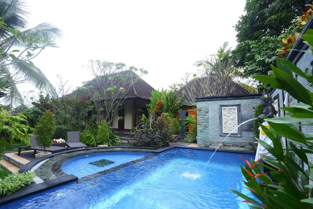 a swimming pool in a garden with a fountain at Loka Sari Guest House and Spa in Ubud