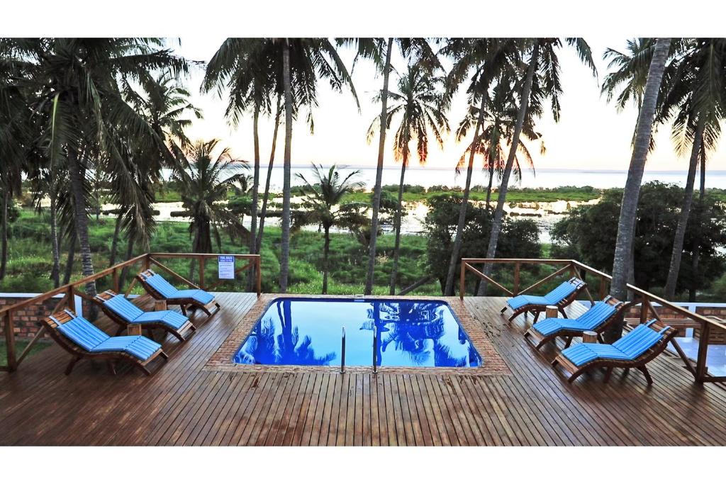 eine Terrasse mit Stühlen und einen Pool mit Palmen in der Unterkunft Vertigo Lodge de Estaurio in Inhambane