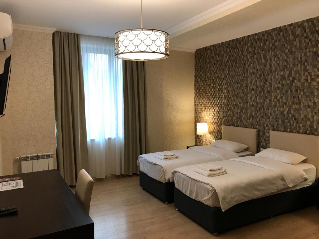 ein Hotelzimmer mit 2 Betten und einem Tisch in der Unterkunft Eleon Boutique Hotel in Tbilisi City