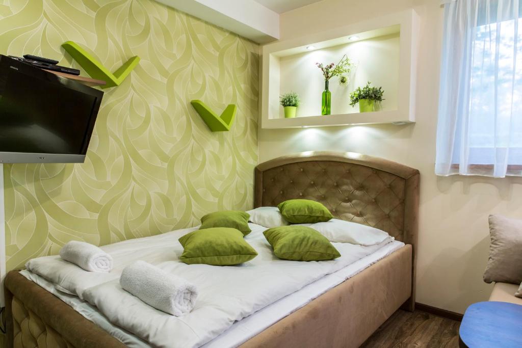 a bedroom with a bed with green and white pillows at Apartament Krupowki CENTRUM in Zakopane