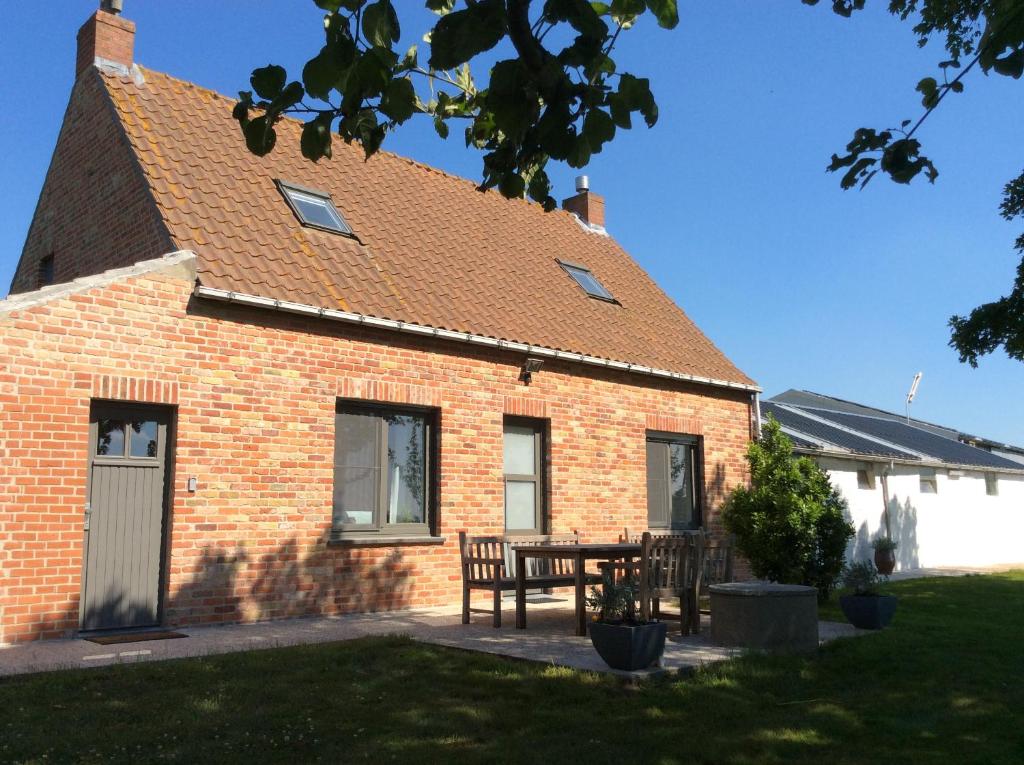 een stenen huis met een tafel en stoelen ervoor bij Valkenhof in Veurne