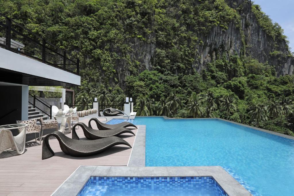 a resort with a swimming pool with a mountain in the background at Lagùn Hotel in El Nido