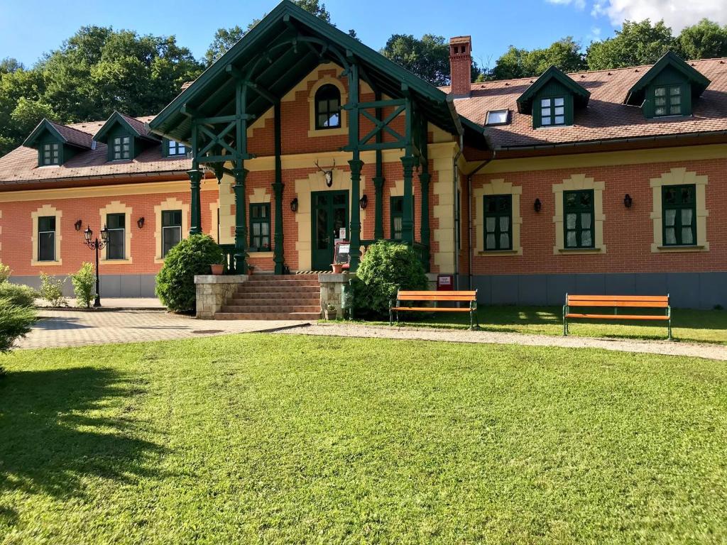 un edificio con dos bancos frente a un patio en St. Hubertus Étterem és Panzió, en Parádsasvár