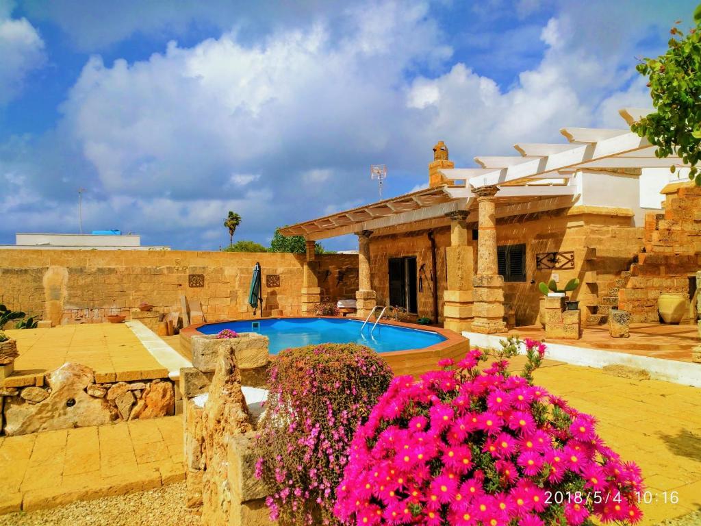 a house with a swimming pool and some pink flowers at Masseria Le Dimore in Gallipoli
