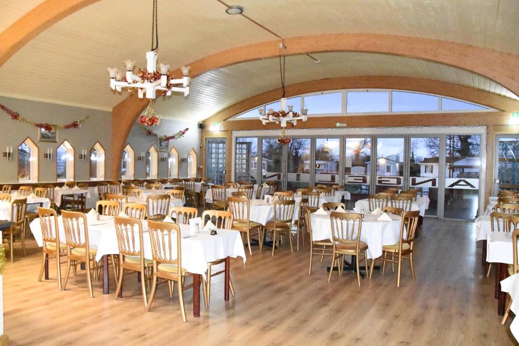 a dining room with white tables and chairs at Warrens Village Motel and Self Catering in Clevedon