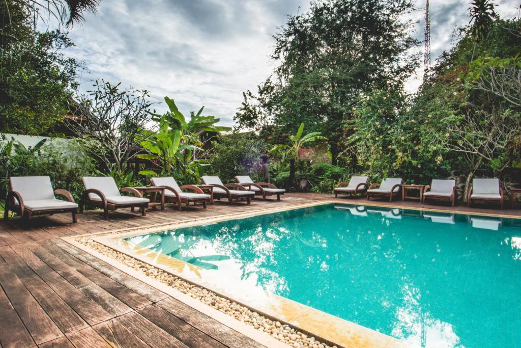 une piscine avec des chaises longues et une piscine dans l'établissement Terres Rouges Lodge, à Banlung