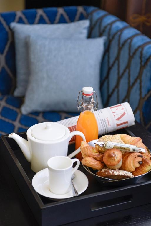 a tray with a plate of breakfast food and a cup of orange juice at Hôtel Tiffany by Fassbind in Geneva