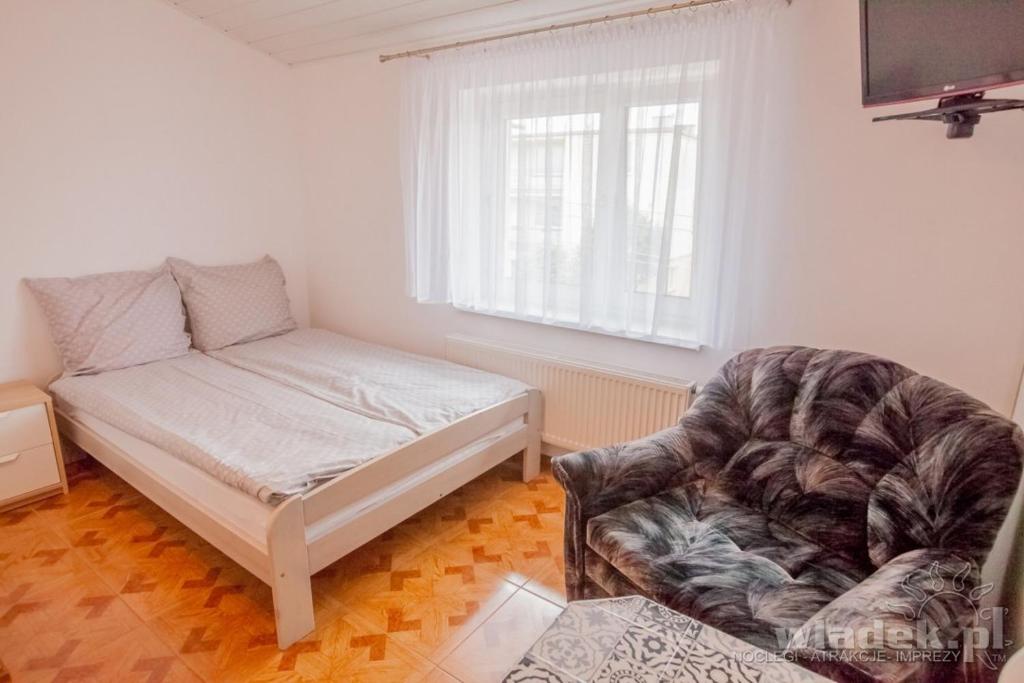 een slaapkamer met een bank, een bed en een stoel bij Pokoje Monika in Władysławowo