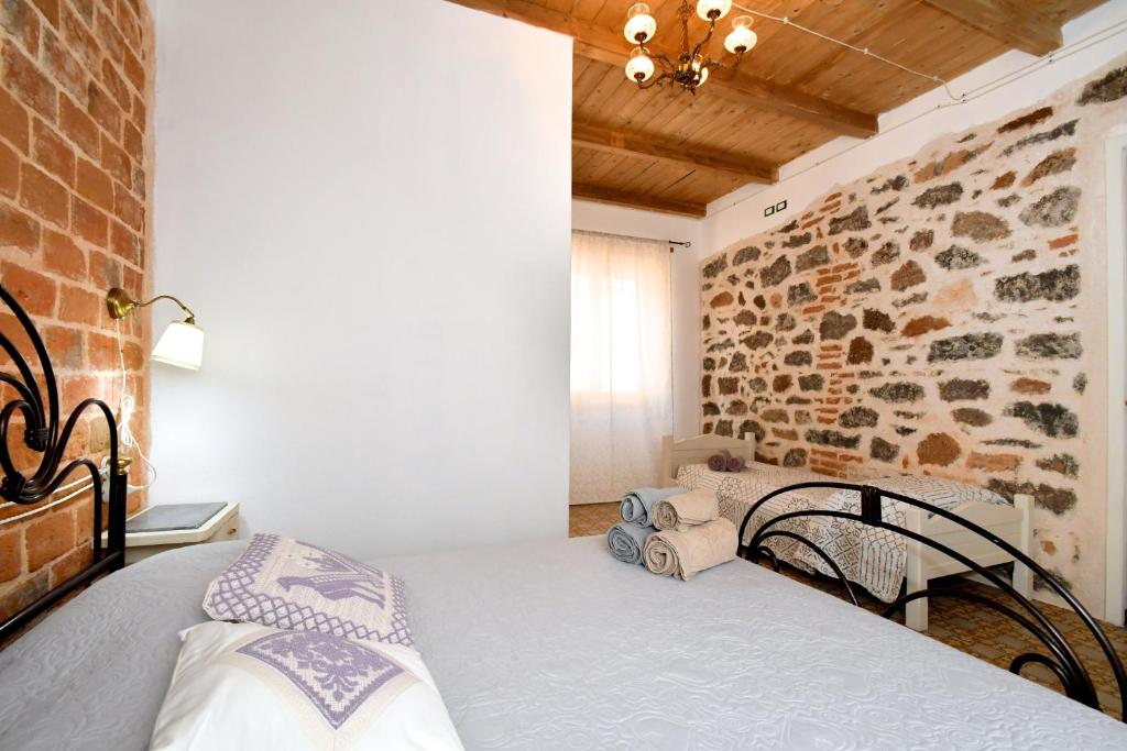 1 dormitorio con cama y pared de ladrillo en B&B Sa domo de sos Massaios, en Orosei
