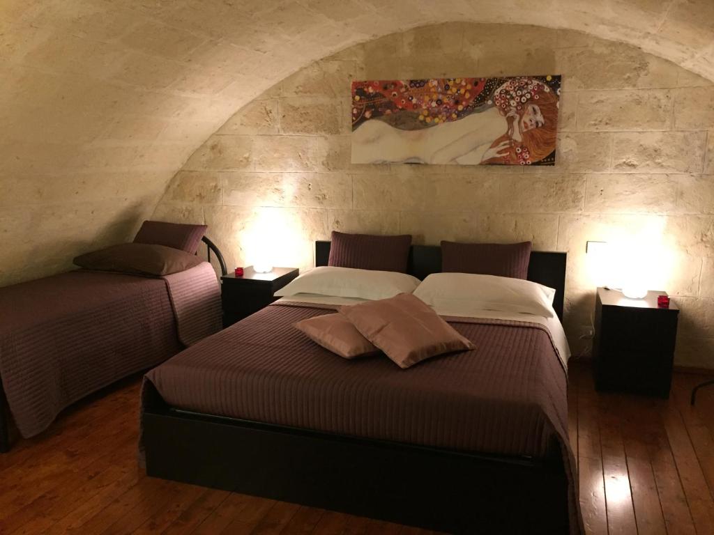 a bedroom with two beds and a painting on the wall at Il Mulino A Vento in Matera