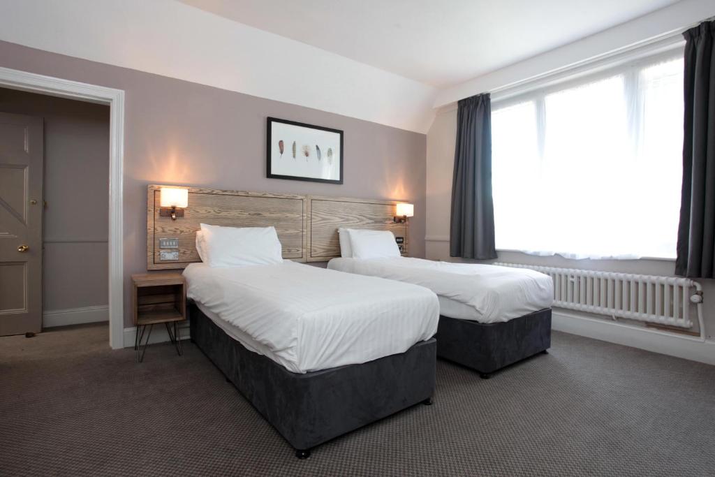 a hotel room with two beds and a window at Bear Inn, Somerset by Marston's Inns in Street