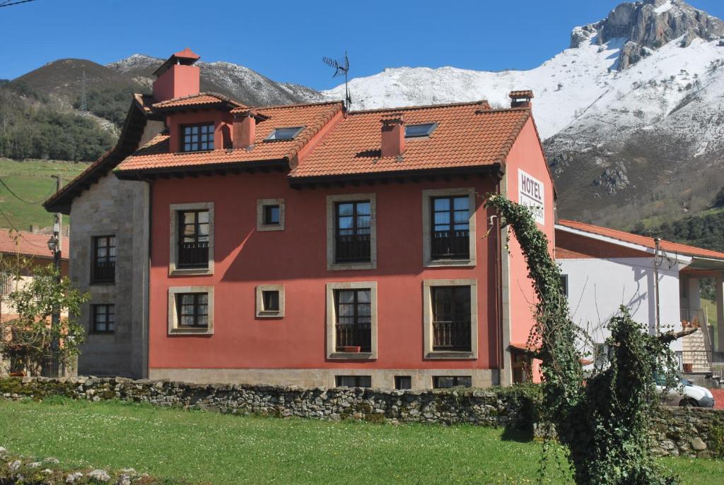 a red house with a mountain in the background at Hotel Los Ángeles in Arenas de Cabrales