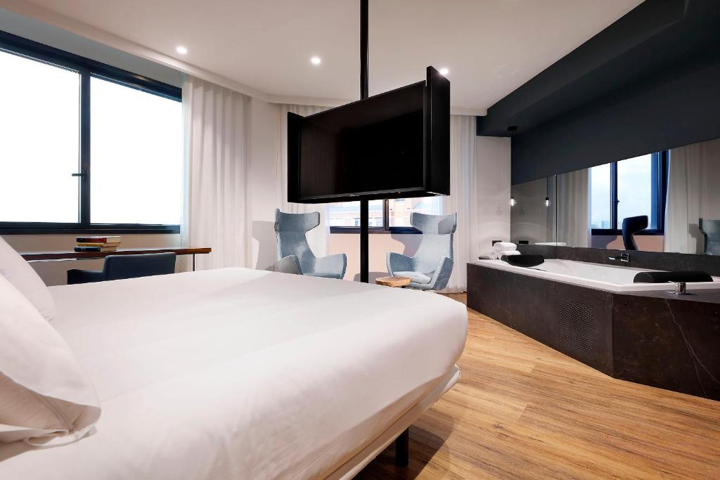 a hotel room with a bed and a tub and a television at Hotel SB Icaria in Barcelona