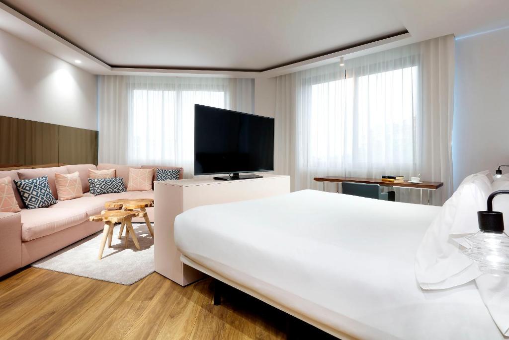 a bedroom with a large white bed and a couch at Hotel SB Icaria in Barcelona