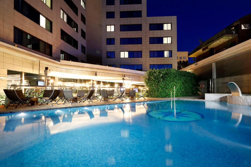 una gran piscina con sillas y un edificio en Hotel SB Icaria, en Barcelona