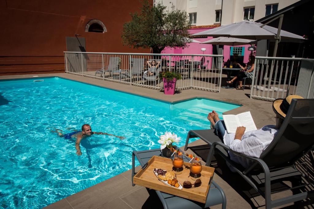 a person is swimming in a swimming pool at Logis Hotels Grand Hotel d'Orléans in Albi