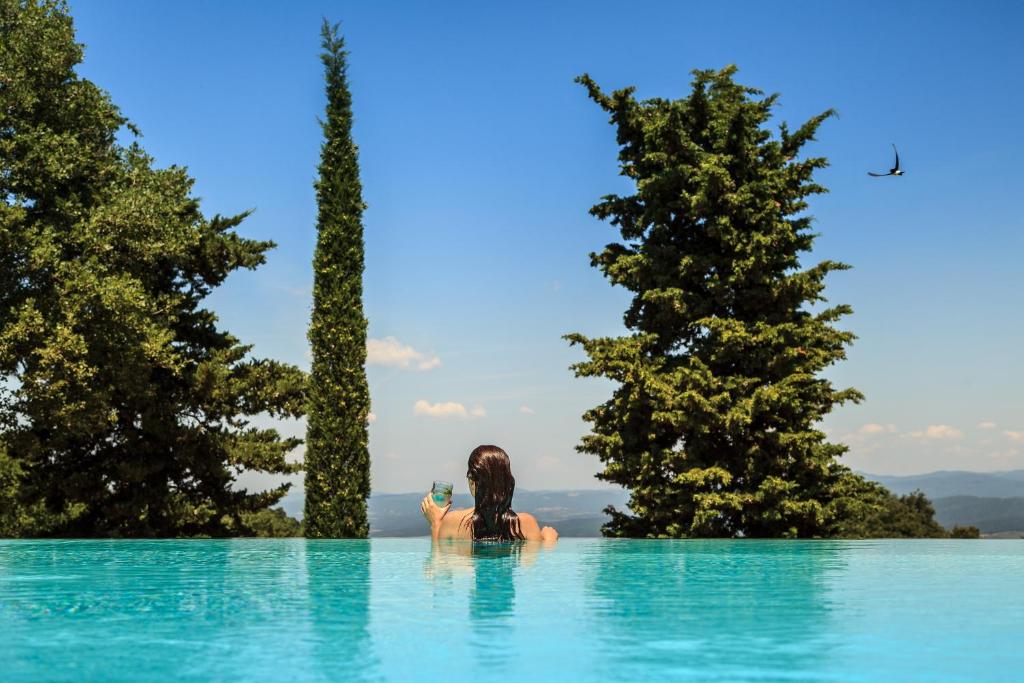 a woman in a swimming pool with trees in the background at Poggio La Croce in Scarlino