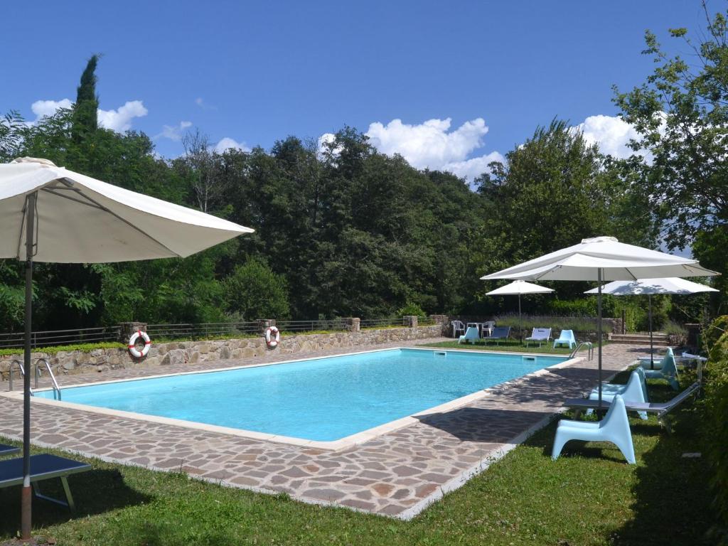 una piscina con 2 sombrillas y sillas en Serene Apartment with Garden Pool Terrace Deckchairs en Lucolena in Chianti