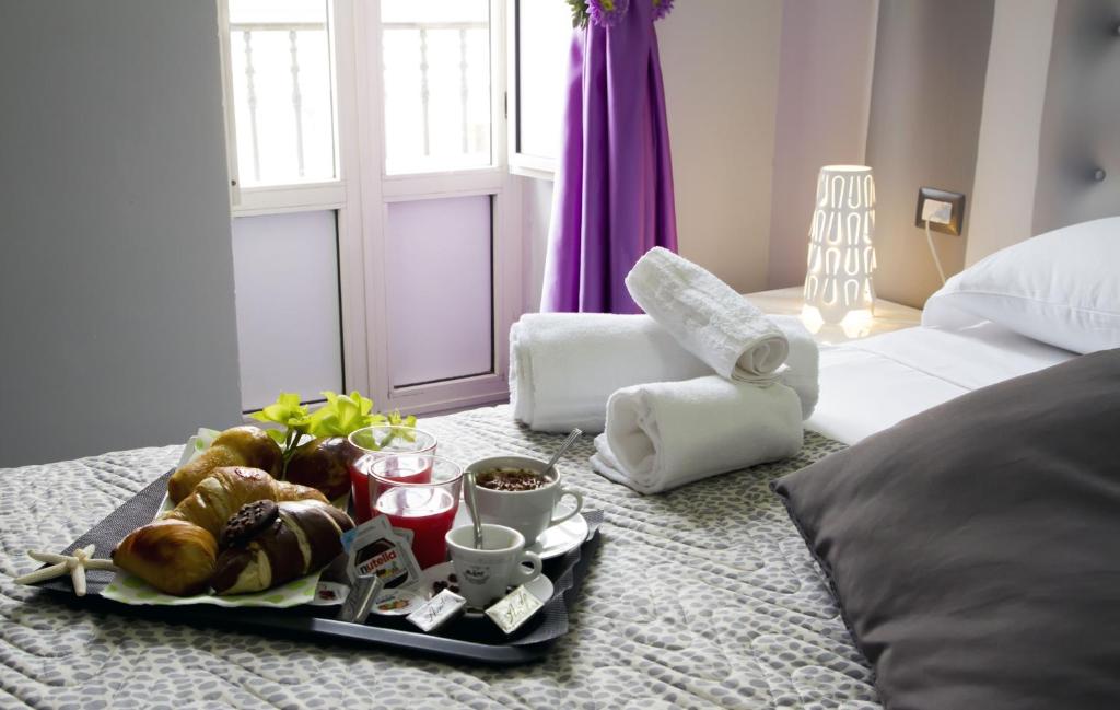a tray with food and drinks on a bed at B&B Napoli Binario 1 in Naples